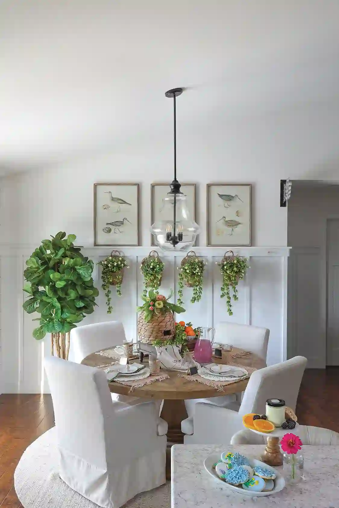 bird prints and baskets with hanging plants serve as decor in dining area of expansive dream home