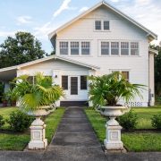 exterior of 1890 farmhouse with potted palms at walkway entrance