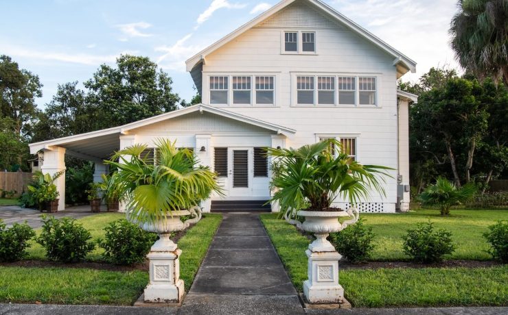 exterior of 1890 farmhouse with potted palms at walkway entrance