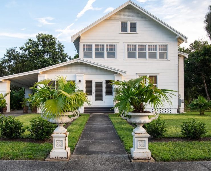 exterior of 1890 farmhouse with potted palms at walkway entrance