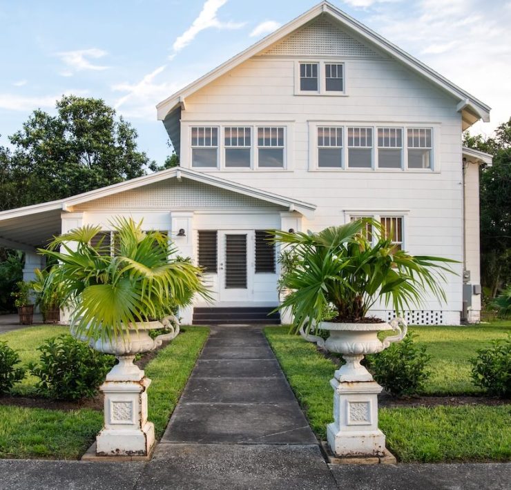 exterior of 1890 farmhouse with potted palms at walkway entrance