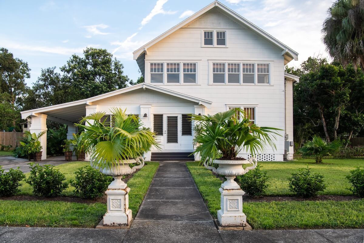 exterior of 1890 farmhouse with potted palms at walkway entrance