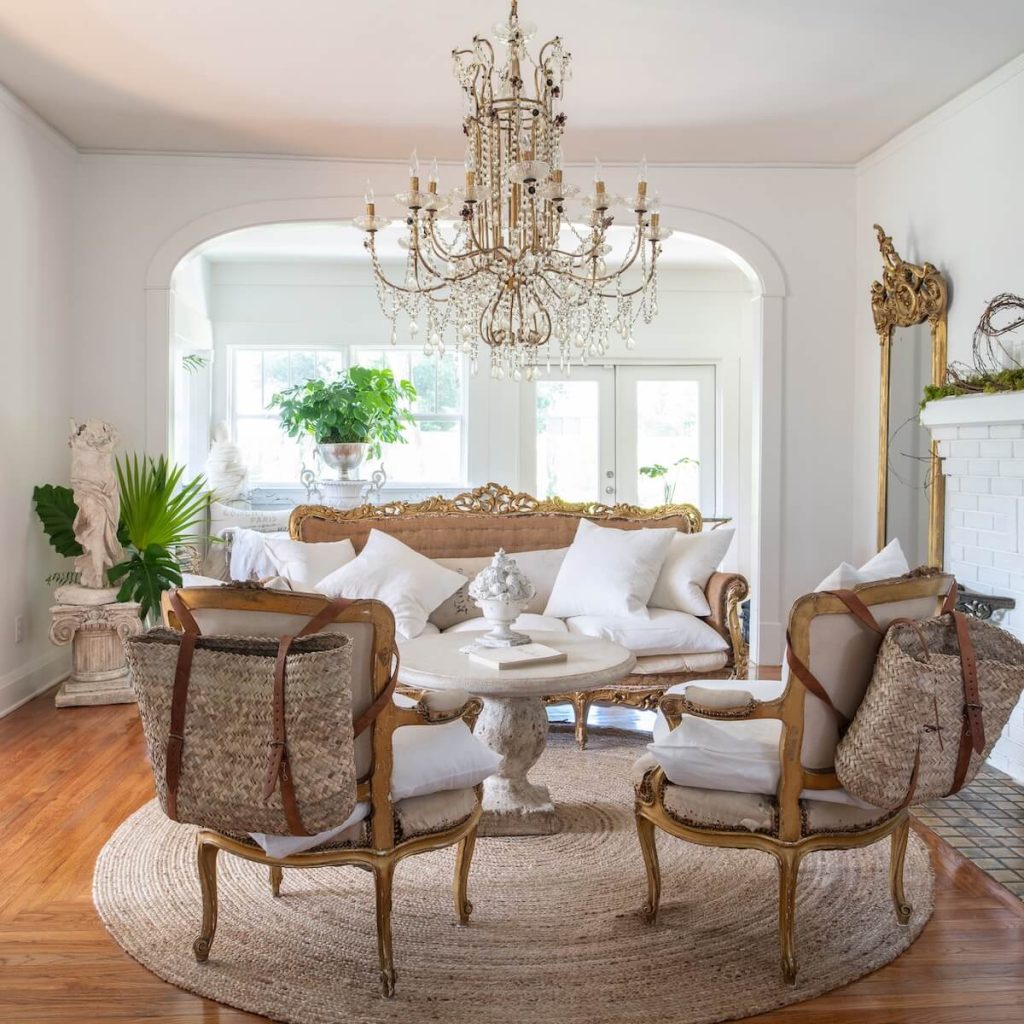 sitting room with potted monstera and palms and European furnishings including large chandelier