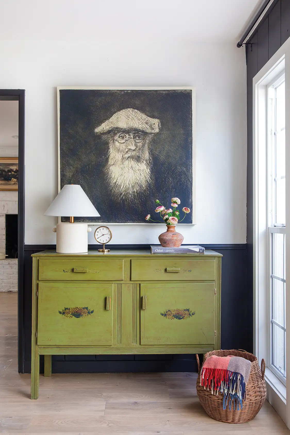 green dresser with black and white portrait framed above it in cozy home with character