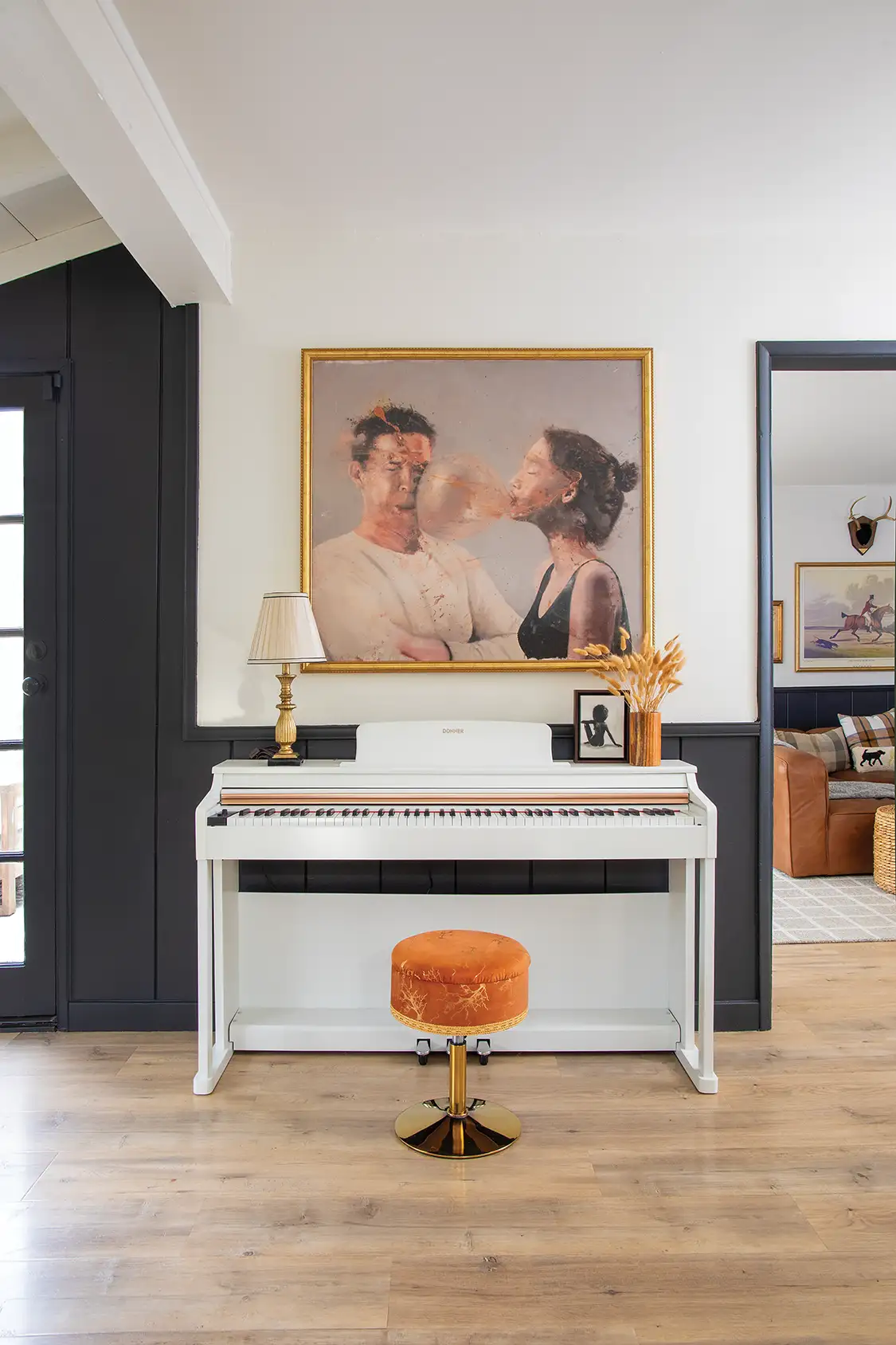 art above piano in renovated home with black contrast against white wall