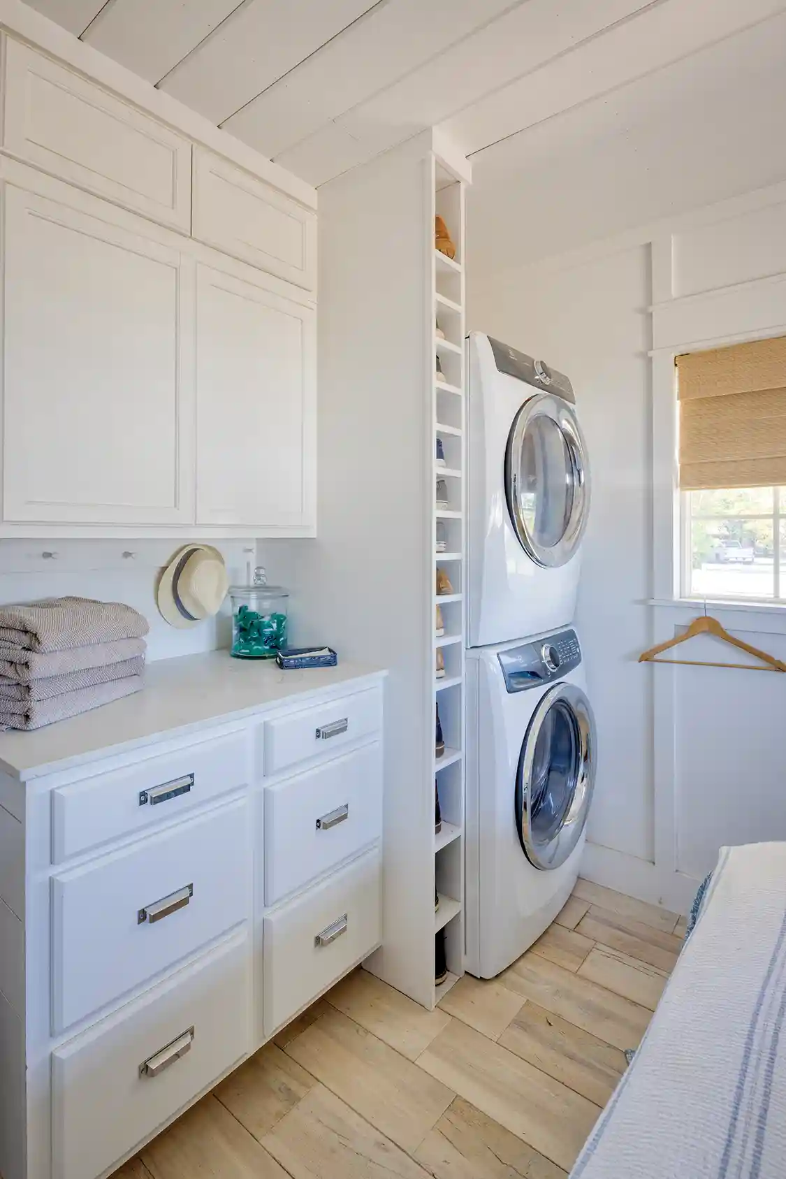 laundry room with stacked washer and dryer and storage drawers and cabinets