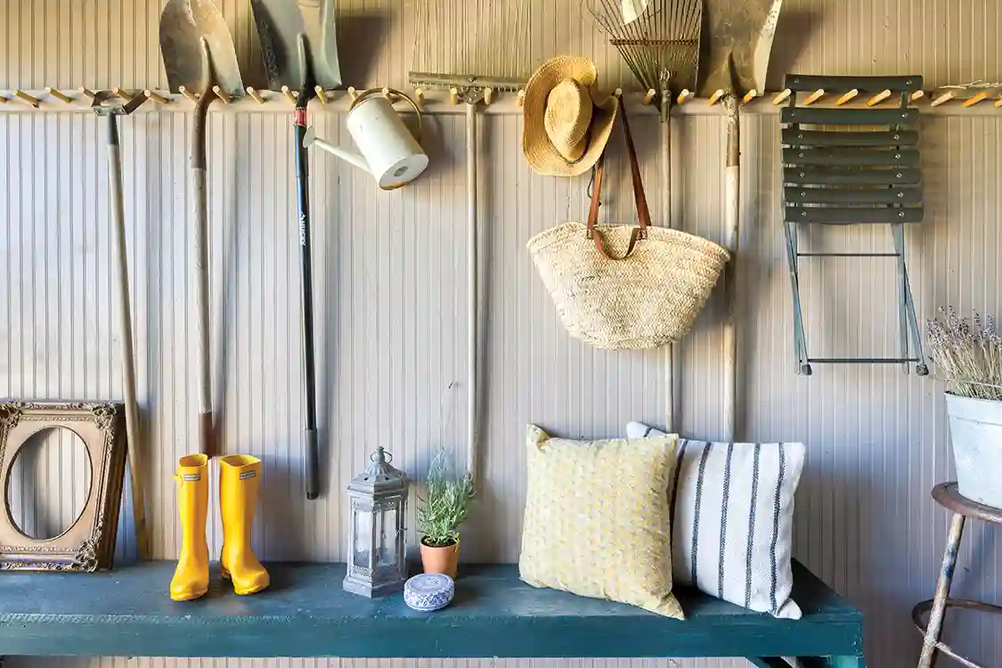 gardening shed with hanging tools and teal bench