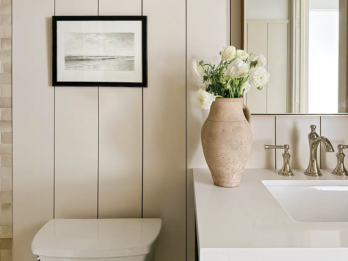 guest bathroom with ceramic vase of flowers, shiplap wall and black and white landscape sketch